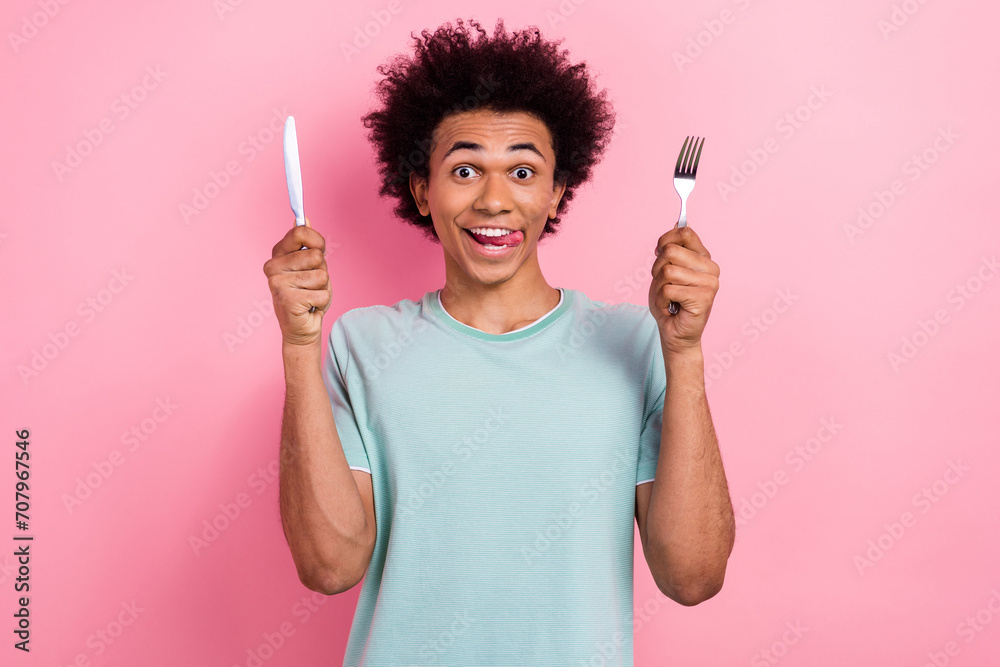 Photo portrait of handsome young male hold fork knife lick tongue hungry dressed stylish blue garment isolated on pink color background - obrazy, fototapety, plakaty 