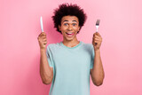Photo portrait of handsome young male hold fork knife lick tongue hungry dressed stylish blue garment isolated on pink color background