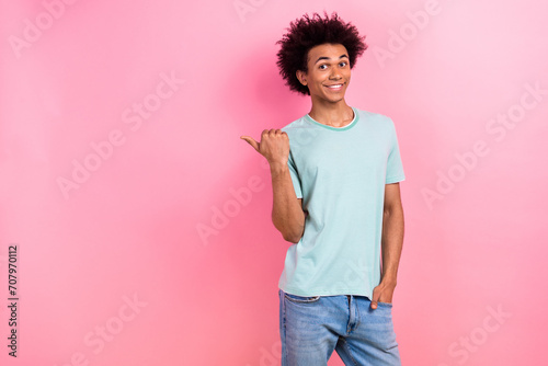 Photo of cheerful funky guy wear blue t-shirt showing thumb empty space isolated pink color background photo