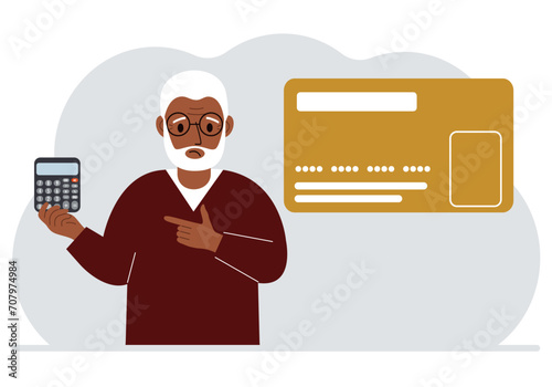 A man holds a calculator in his hand. Nearby is a large plastic card.