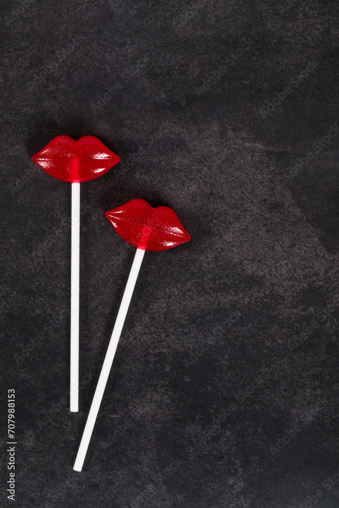 Two Red lips lollipops on a paper stick. Couple. Dark gray background. Top view. Copy space. Valentine's day Two Red lips lollipops on a paper stick. Couple. Dark gray background. Top view. Copy space. Valentine's day