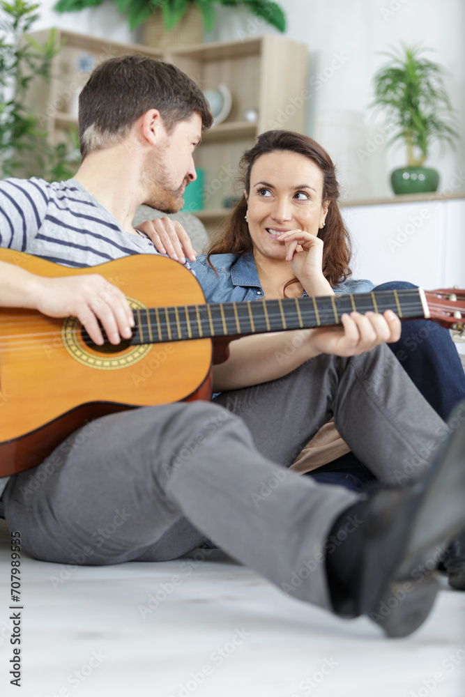 Fototapeta premium young couple playing guitar on couch indoor