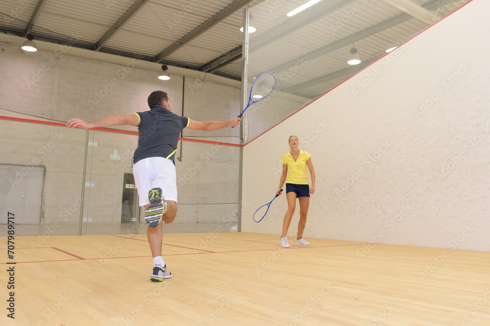 couple playing squash on indoor court couple playing squash on indoor court