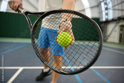 Unrecognizable man holding tennis ball and racket training serving skills © Viacheslav Yakobchuk
