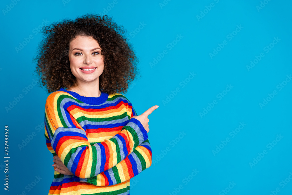 Photo portrait of lovely young lady point cheerful empty space wear trendy rainbow print garment isolated on blue color background Photo portrait of lovely young lady point cheerful empty space wear trendy rainbow print garment isolated on blue color background