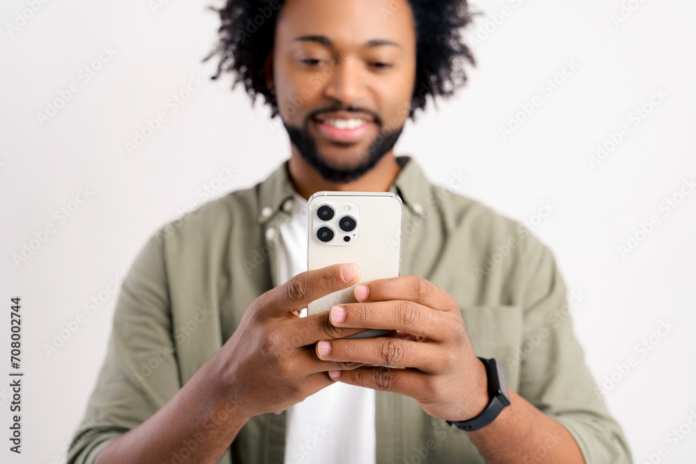 Portrait view of young adult man looking at mobile phone with happy astonished expression. Indoor studio shot isolated on white background Portrait view of young adult man looking at mobile phone with happy astonished expression. Indoor studio shot isolated on white background