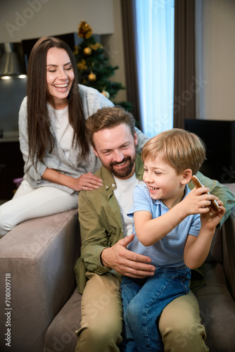 Laughing woman and man enjoying happy Christmas time with their son in hotel