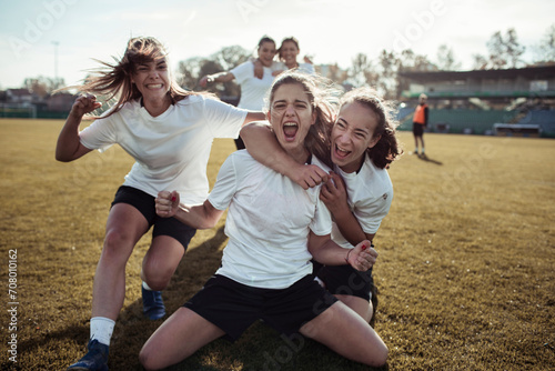 Young female football team celebrating a goal on the soccer field