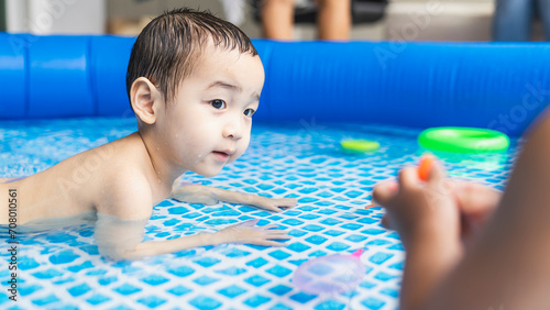 Happy little Asian boy swimming in the pool, relaxation in summer.