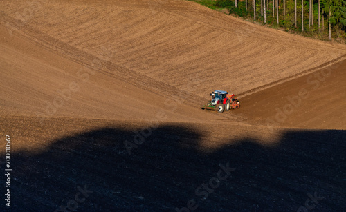 Red tractor an a brownish field in Sauerland, Germany. Panoramic aerial view with farmer and his machine tilling the land and plowing the soil in bright sunshine. Agriculture in rural landscape. © ON-Photography