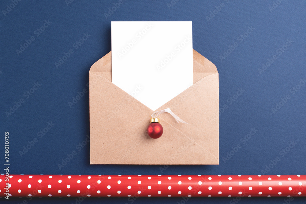 Obraz na plátně Christmas composition with kraft paper envelope, white card and red New Year decorations on dark blue background
