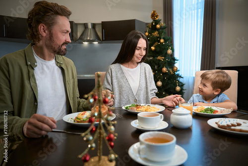 Family holding hands and praying before festive Christmas dinner at home