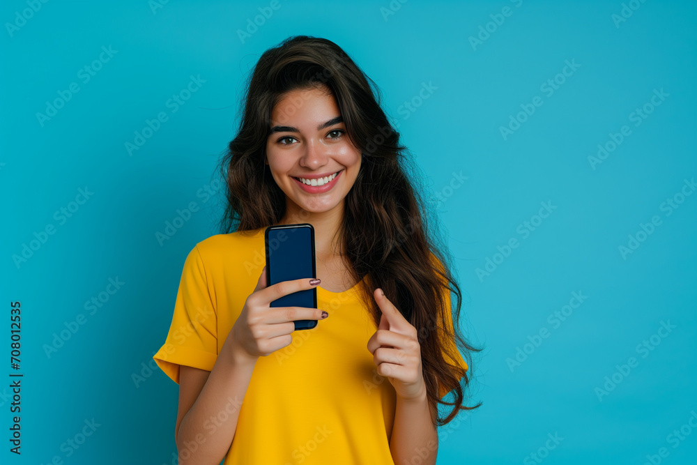 girl smiling with cell phone, raising a finger on blue background girl smiling with cell phone, raising a finger on blue background