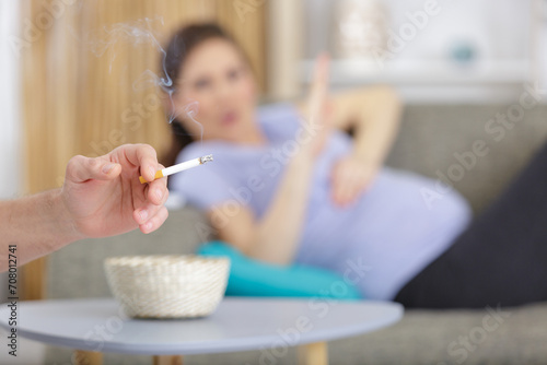 young pregnant women raise her hand against smoke photo