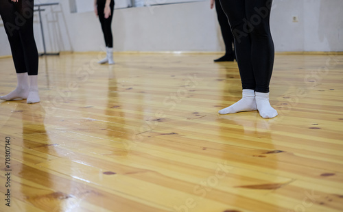 Contemporary dance workout. Woman's feet in white socks on the parquet floor. Shallow depth of field. Copy space.