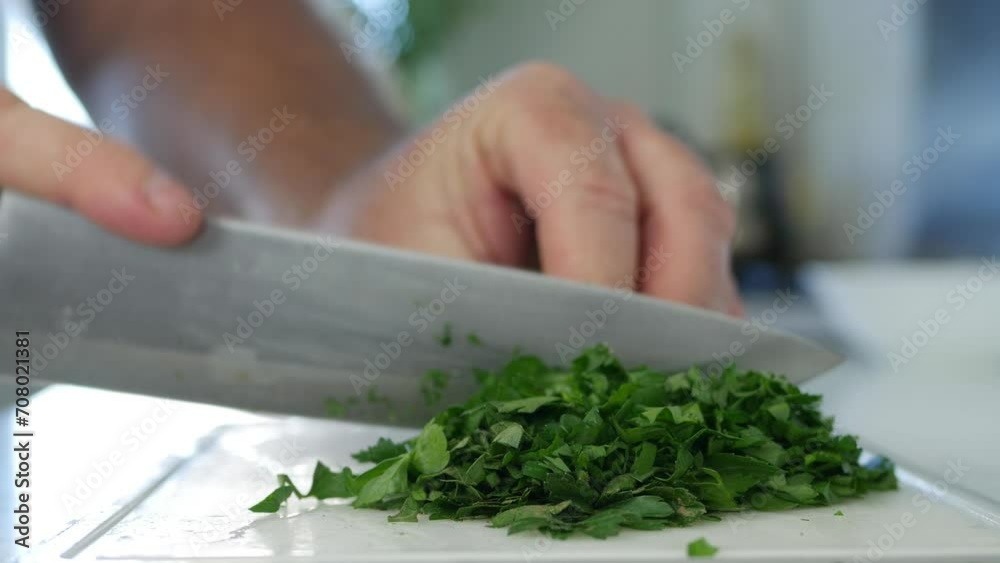 Blurred Shooting with a Man Chopping Fresh Green Parsley Leafs in the Kitchen. Green Flavored Parsley Leafs, Chopped Herbs Prepared for a Fresh and Full with Vitamins Vegan Salad. Blurred Shooting with a Man Chopping Fresh Green Parsley Leafs in the Kitchen. Green Flavored Parsley Leafs, Chopped Herbs Prepared for a Fresh and Full with Vitamins Vegan Salad.