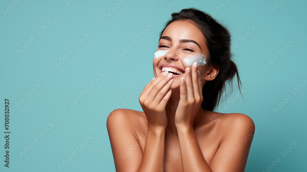 The image depicts a joyful young woman applying facial cream, with a bright and playful expression. The image depicts a joyful young woman applying facial cream, with a bright and playful expression.