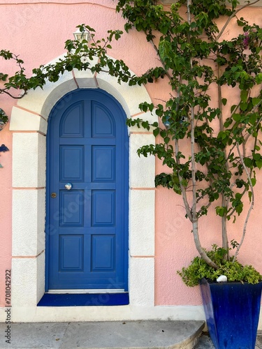 Blue wooden door in an arched doorway of a pink house, Assos village, Kefalonia island, Greece