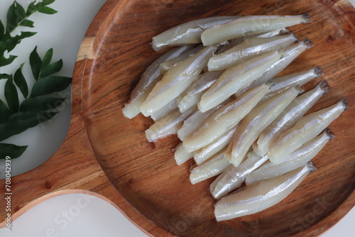 Freshly cut and cleaned anchovy fish presented on a rustic wooden tray photo