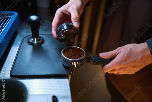 Slika na platnu Barista holding portafilter and coffee tamper making espresso coffee in cafe