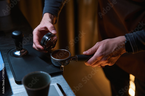 Unrecognizable coffee maker hands holding portafilter and coffee tamper