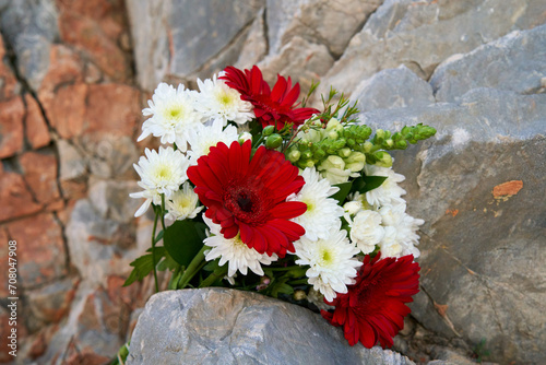 a beautiful bouquet of red gerberas and white chrysanthemums against a background of beautiful rocks