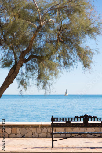 paseo marítimo de Fuengirola con un banco para descansar y al fondo el mar con un velero en el horizonte. © tingitania