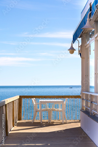 Chiringuito o restaurante de playa con sus mesas ,sillas y sombrilla mirando al mar mediterráneo con el horizonte al fondo y un día luminoso de sol photo