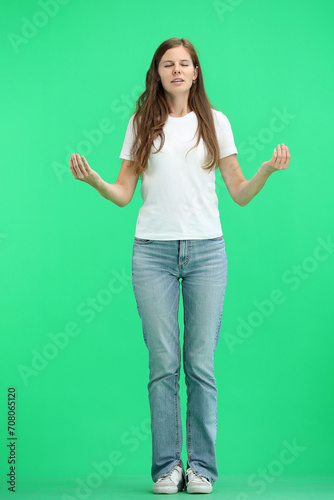 A woman, full-length, on a green background, spreads her arms
