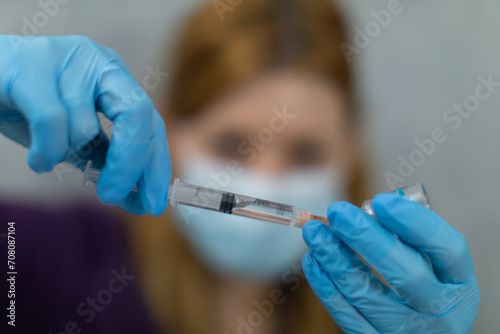 The woman holds her hands in front of her and holds a syringe and a vial in them.