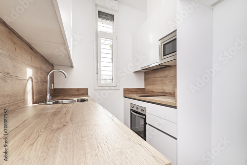 Newly renovated small kitchen with white wooden cabinets, wooden countertop with splashbacks