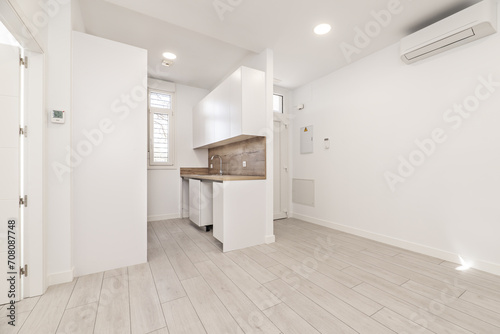 A loft-style home with a newly installed small kitchen in a corner with light gray parquet floors