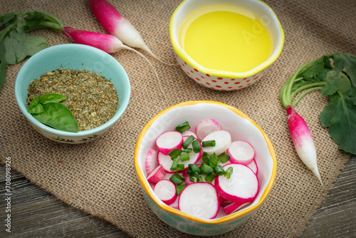 Salad of raddishes and onion, herbs and oil on the wooden table. photo