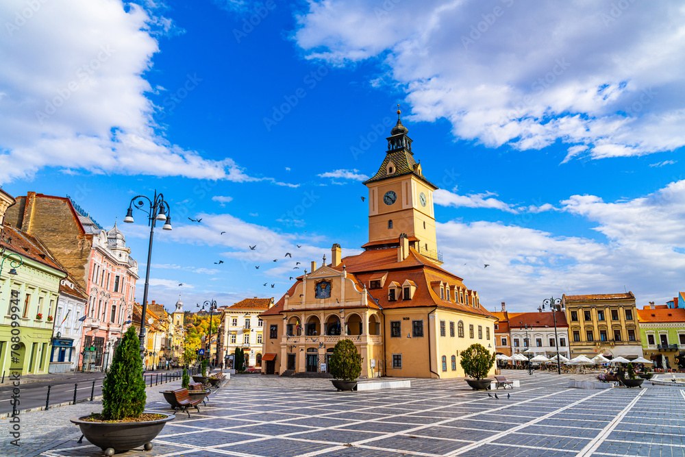Clock Tower in the Picturesque Brasov Town Square. An enchanting image featuring the iconic clock tower situated in the lively town square of Brasov, Romania, in the heart of Transylvania.