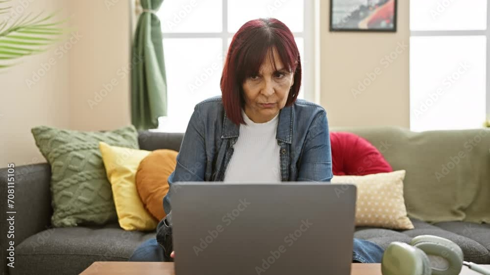 Mature hispanic woman using laptop in a cozy living room, expressing surprise and focus. Mature hispanic woman using laptop in a cozy living room, expressing surprise and focus.