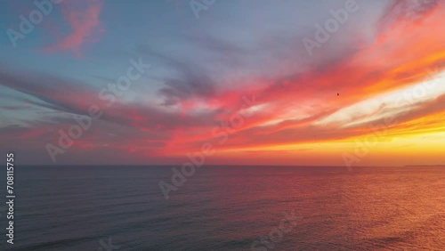 Vibrant colorful sunset clouds over the ocean in Portimao. Flock of seagulls flying away photo