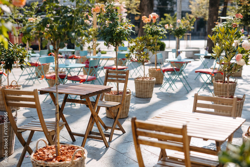 Outdoor café with wooden tables and chairs surrounded by potted plants.