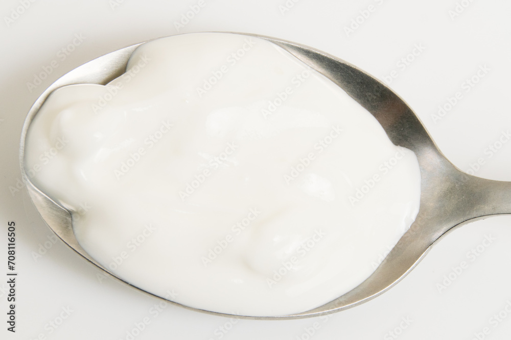 Sour cream or white sauce in a spoon on a white plate close-up Sour cream or white sauce in a spoon on a white plate close-up