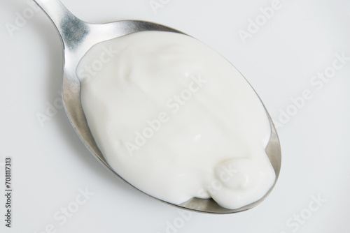 Sour cream or white sauce in a spoon on a white plate close-up