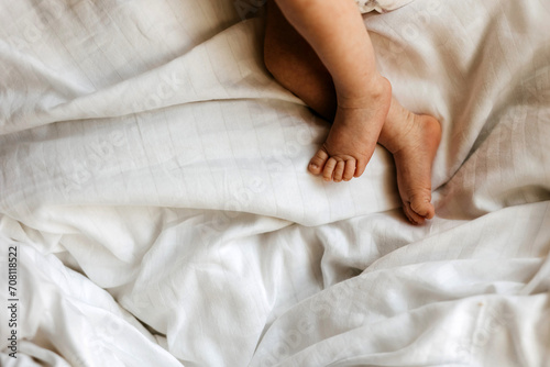 A baby's tiny feet and toes on soft white cotton bedsheet. © Bostan Natalia