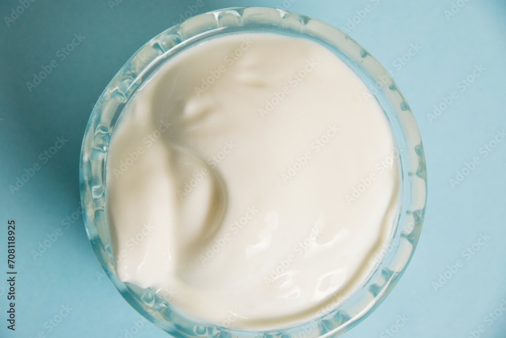 White sauce in a glass saucer on a blue background White sauce in a glass saucer on a blue background