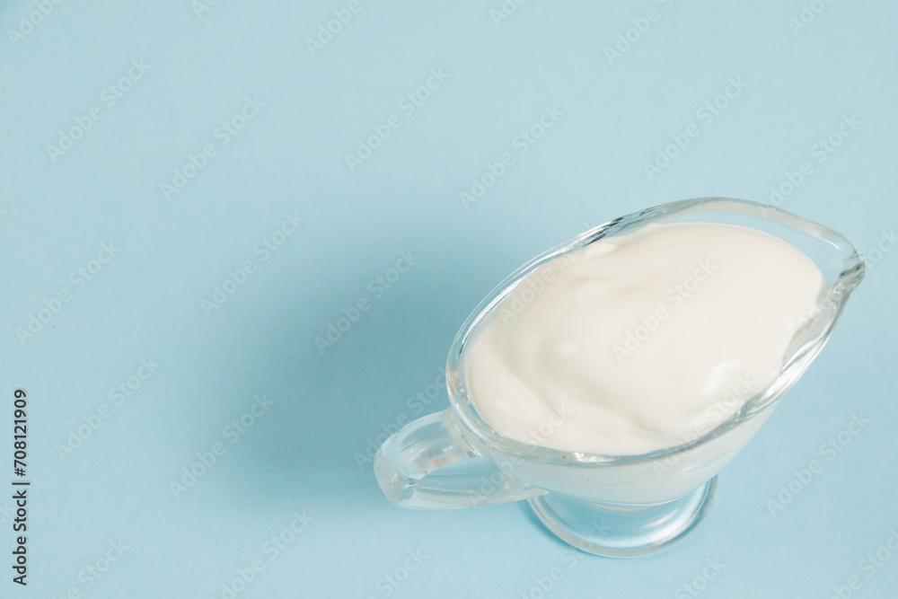 White sauce in a glass saucer on a blue background White sauce in a glass saucer on a blue background