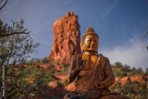 This image shows a front view of a buddha statue with a scenic mountain landscape in the background.