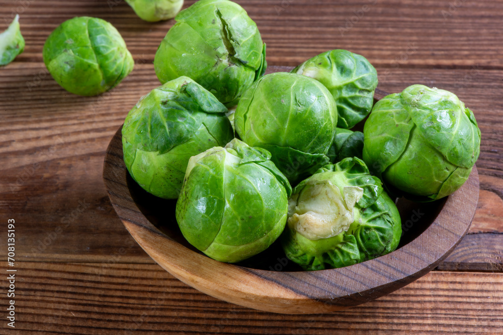 Fresh organic brussels sprouts raw in a plate on wooden background Fresh organic brussels sprouts raw in a plate on wooden background