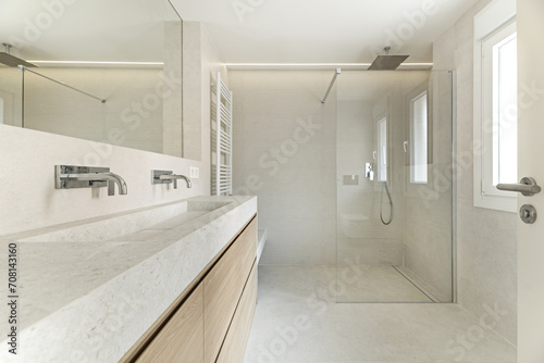 Modern design bathroom with a mirror integrated into the wall  cream-colored tiled walls and floors