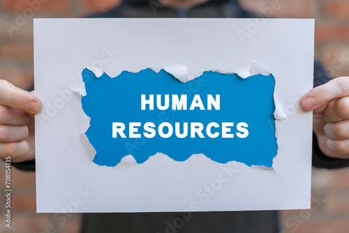 Business search human resources management social network concept. Man holding white and blue sheets of paper with text: HUMAN RESOURCES. HR job vacancy find internet technology. photo