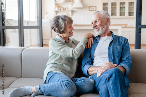 Cheerful caucasian senior old elderly couple spouses grandparents hugging embracing cuddling, spending time together while relaxing resting on the sofa couch photo