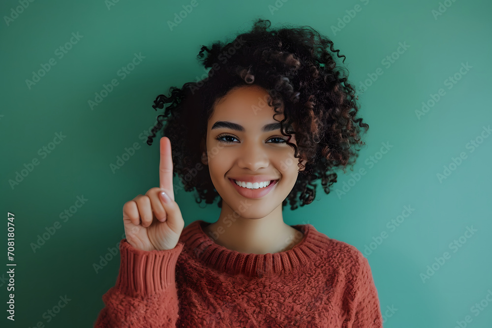 Obraz premium young happy woman holding her finger up over green background