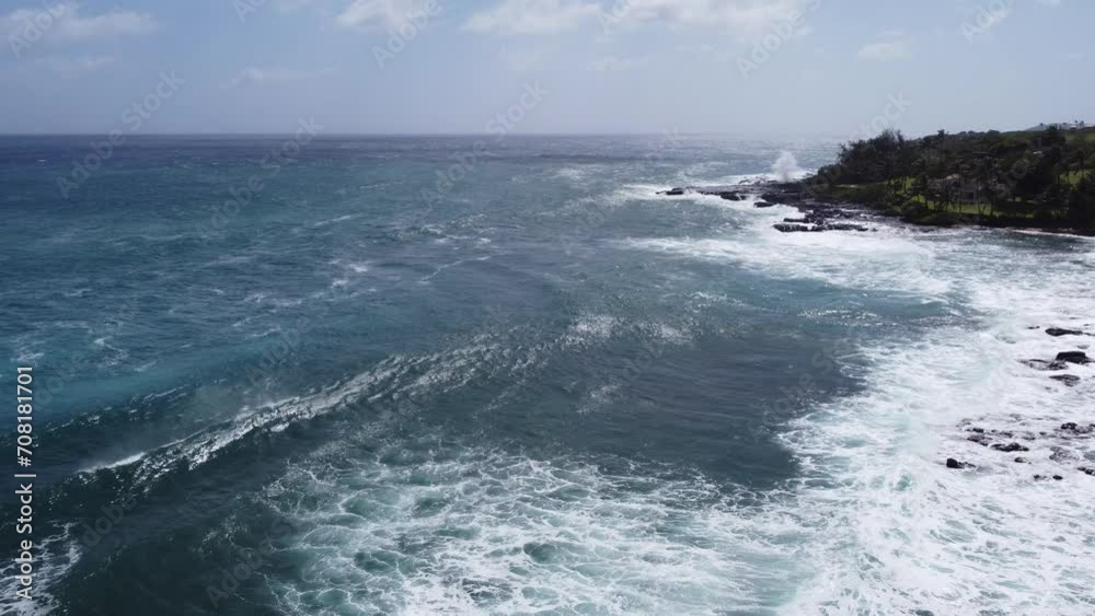 Aerial view captured by drone of large whitecap ocean waves in the Pacific ocean violently crashing into the rocky shore on the coast of Kauai in Hawaii at Spouting Horn. Aerial view captured by drone of large whitecap ocean waves in the Pacific ocean violently crashing into the rocky shore on the coast of Kauai in Hawaii at Spouting Horn.