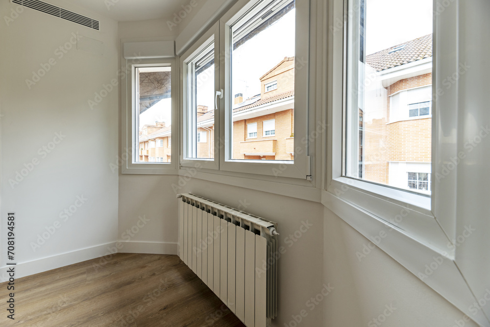 An empty room with a gallery full of windows with aluminum radiators An empty room with a gallery full of windows with aluminum radiators